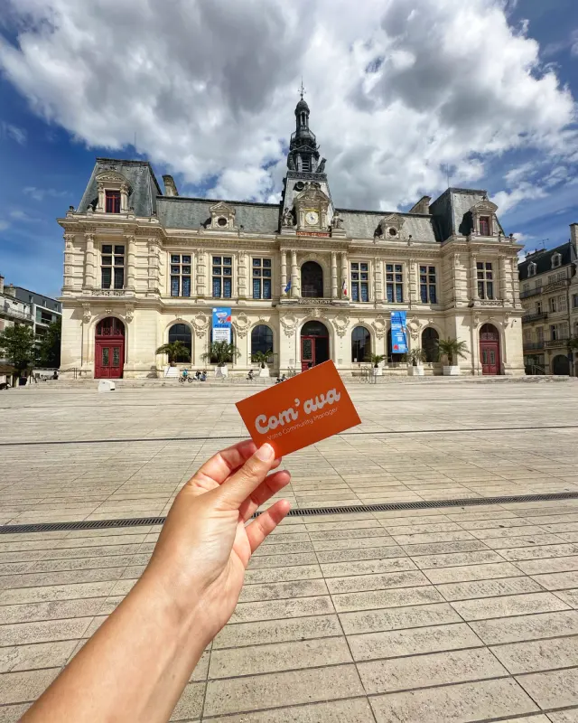 Carte de visite de Com'Ava avec la mairie de Poitiers en arrière-plan, illustrant l'activité de community manager freelance à Poitiers